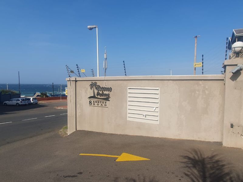 Street view of the property entrance featuring a perimeter wall, electric fencing, and security gate access.
