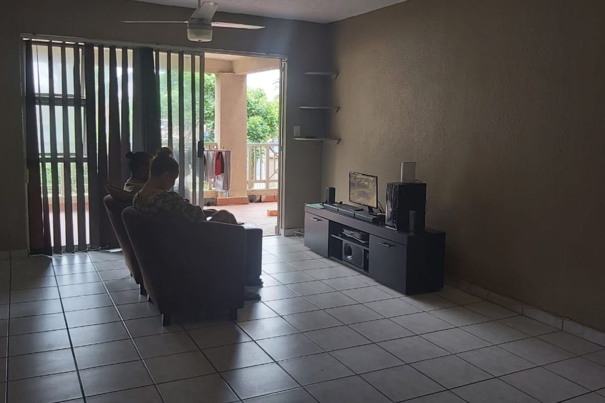 A living room featuring tiled flooring, a ceiling fan, and a sliding glass door providing access to an outdoor balcony area.