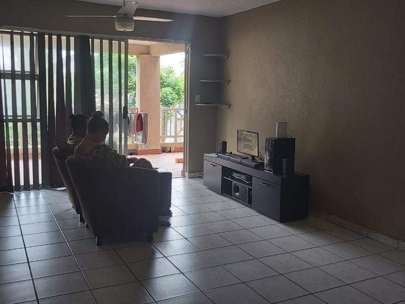 A living room featuring tiled flooring, a ceiling fan, and a sliding glass door providing access to an outdoor balcony area.