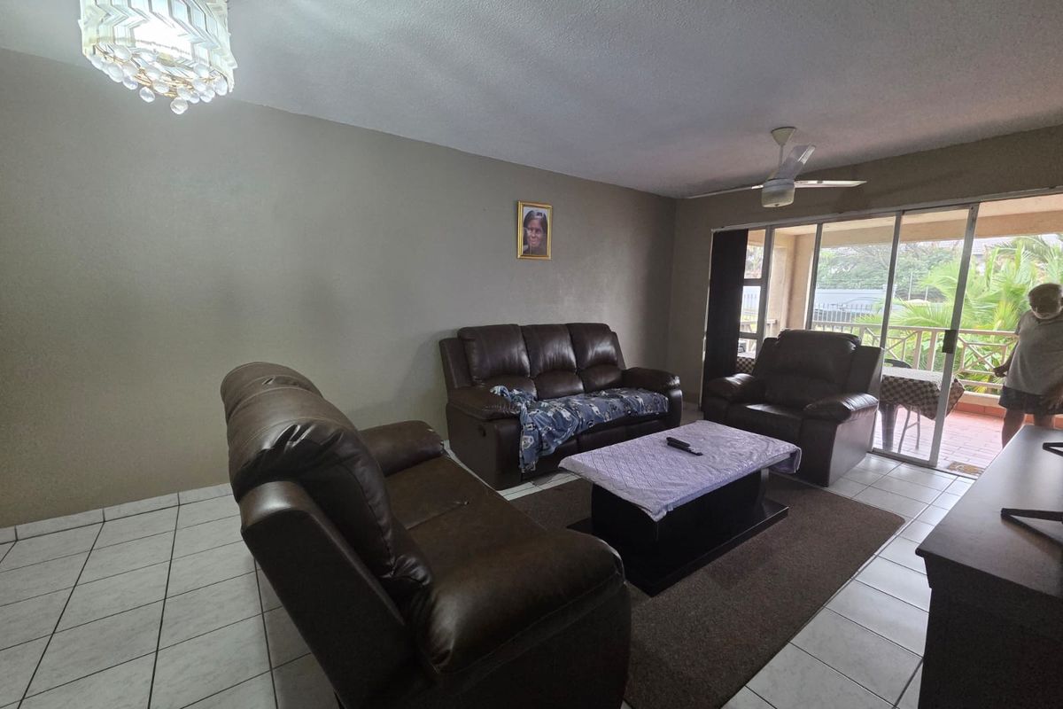 Spacious living room featuring tiled flooring, a ceiling fan, and large sliding glass doors providing access to an outdoor patio area.