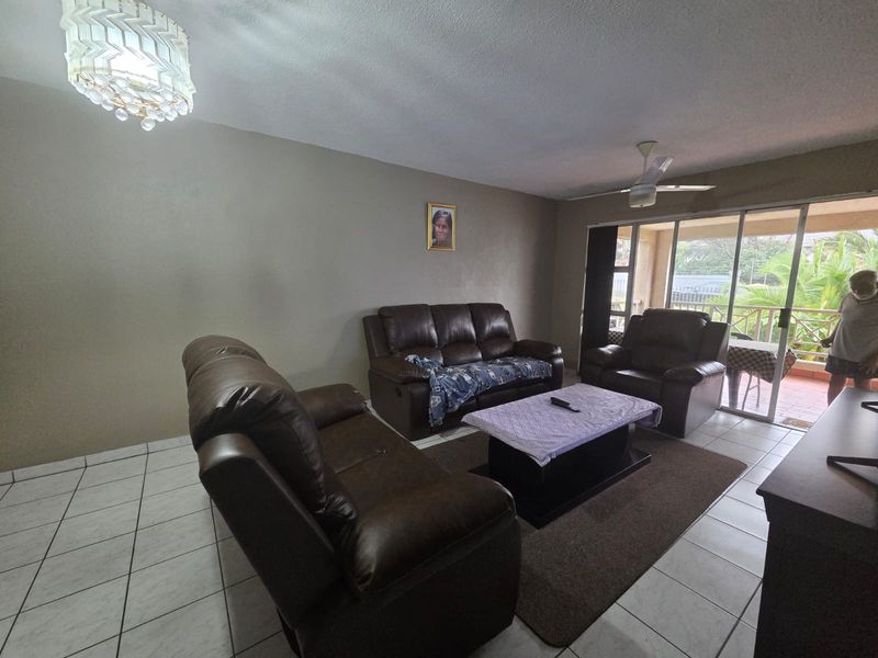 Spacious living room featuring tiled flooring, a ceiling fan, and large sliding glass doors providing access to an outdoor patio area.
