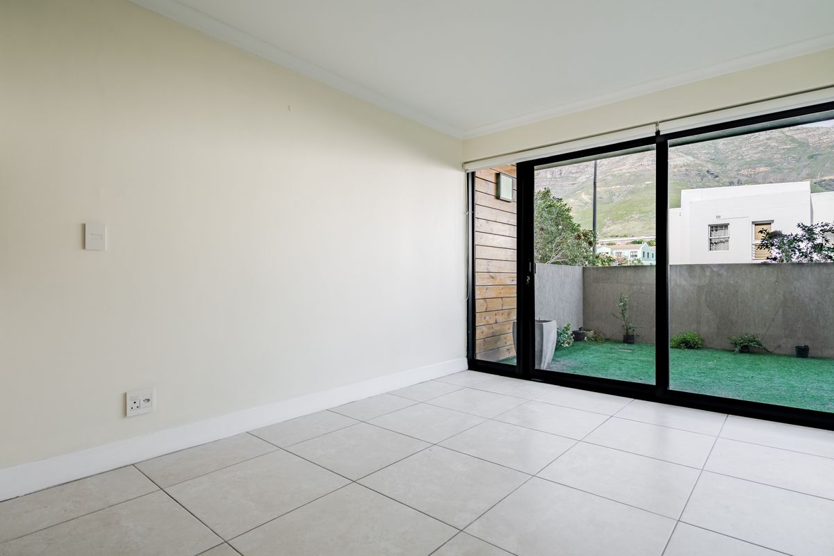 Bright and spacious living area featuring neutral tiled flooring and large sliding glass doors that provide direct access to a private outdoor patio space.