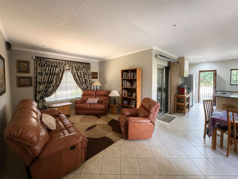 Spacious open-plan living and dining area featuring tiled flooring, recessed lighting, and seamless flow to the kitchen and outdoor access.