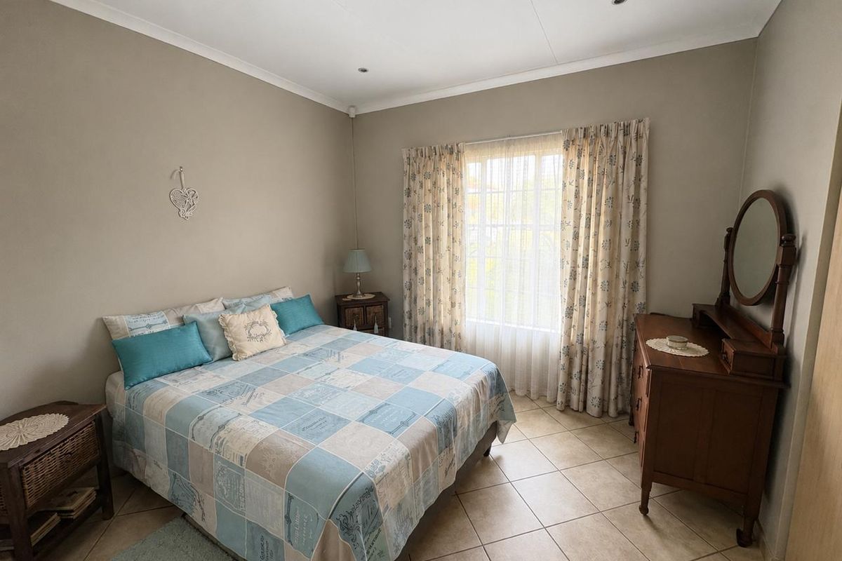 A well-maintained bedroom featuring neutral wall tones, tiled flooring, and recessed ceiling lighting, offering a clean and functional living space.