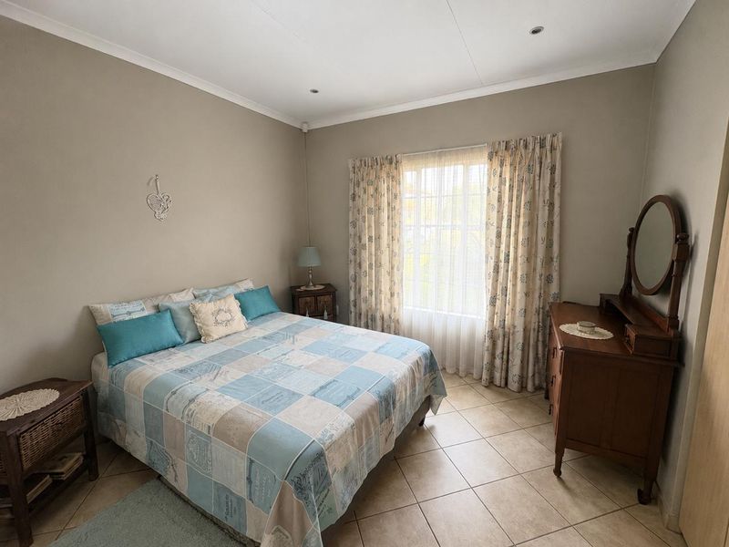 A well-maintained bedroom featuring neutral wall tones, tiled flooring, and recessed ceiling lighting, offering a clean and functional living space.