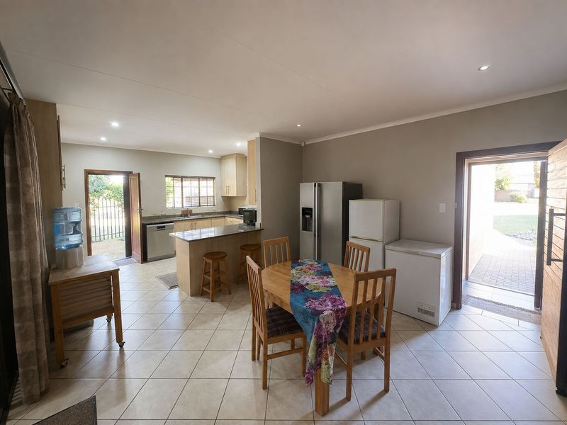 Open-plan kitchen and dining area featuring tiled flooring, granite countertops, built-in cabinetry, and direct access to the outdoor garden space.