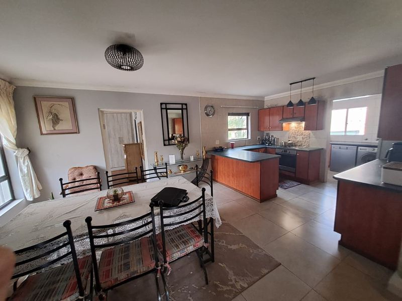 Open-plan dining and kitchen area featuring wooden cabinetry, laminate countertops, built-in oven, and tiled flooring throughout.
