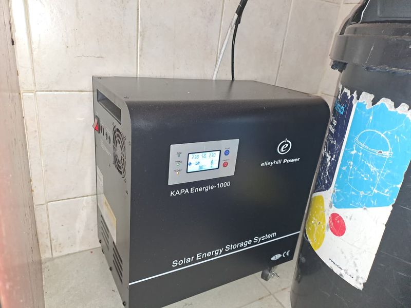 A wall-mounted solar energy storage system unit installed in a utility area with tiled wall finishes.