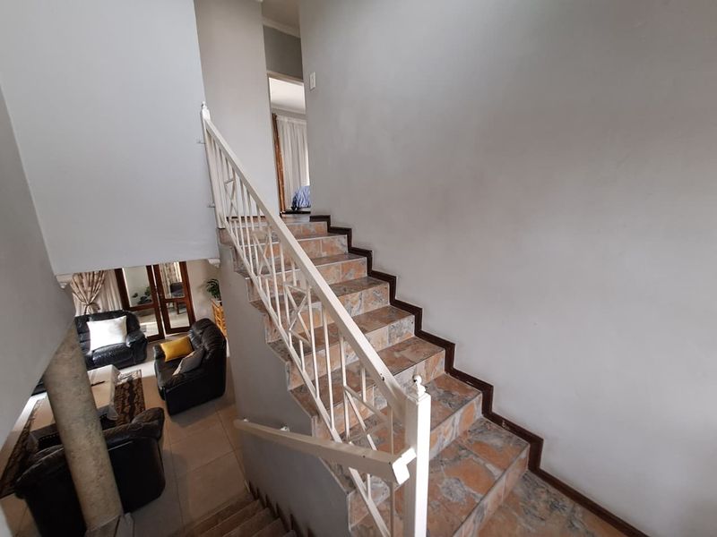 A staircase with tiled treads and a white metal balustrade connecting the levels of the townhouse.