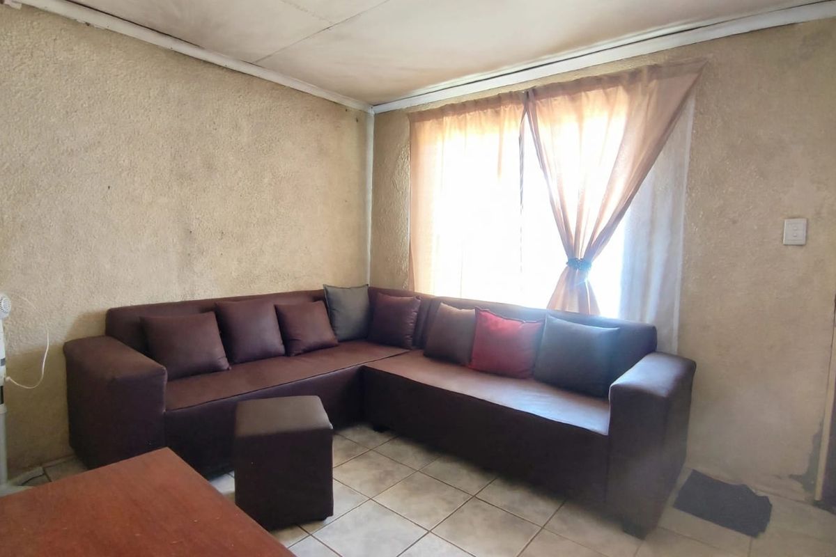 A living room featuring tiled flooring and textured walls, offering a functional space that could benefit from cosmetic updates to enhance its appeal.