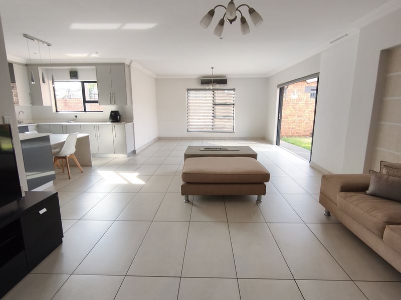 Spacious open-plan living area featuring a modern kitchen with island, tiled floors, and large sliding doors opening to the rear garden.