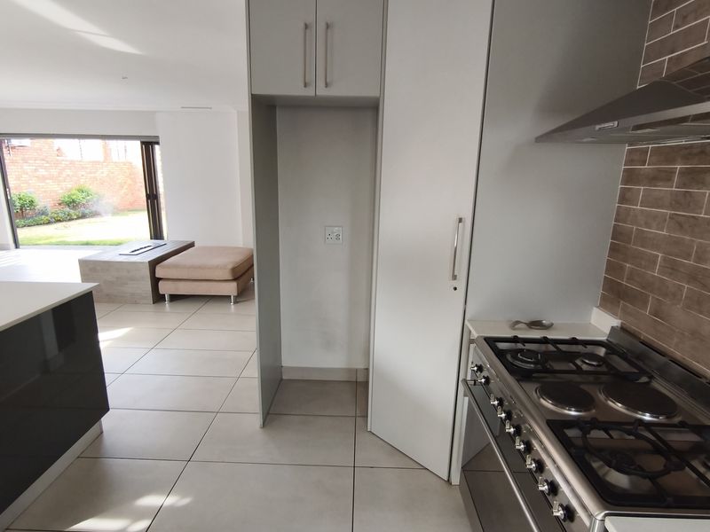 Modern kitchen featuring gas stove, extractor fan, and ample built-in cabinetry, seamlessly flowing into an open-plan living area with garden access.
