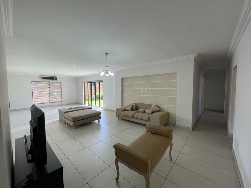 Spacious living area featuring neutral tiled flooring, a decorative recessed wall feature, and sliding glass doors providing access to the exterior.