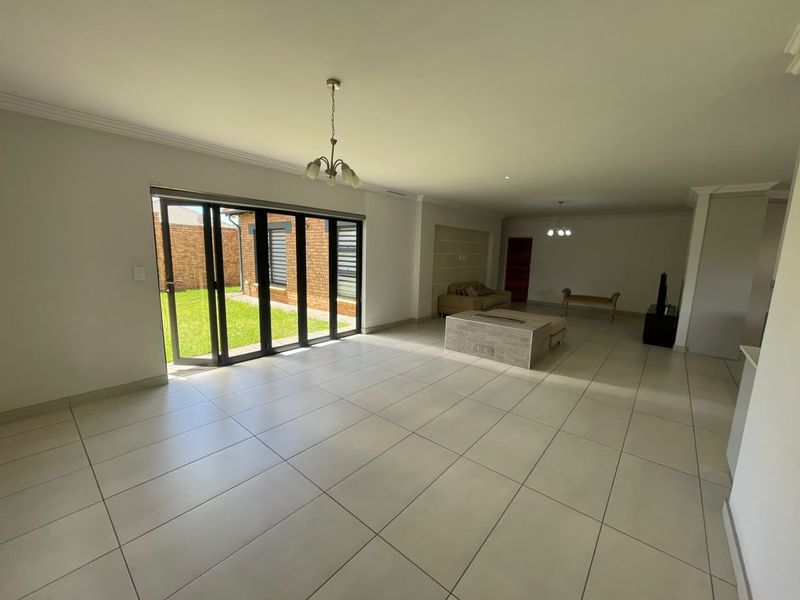 Spacious open-plan living area featuring large bi-fold glass doors leading to the garden, tiled flooring, and a central built-in fireplace.