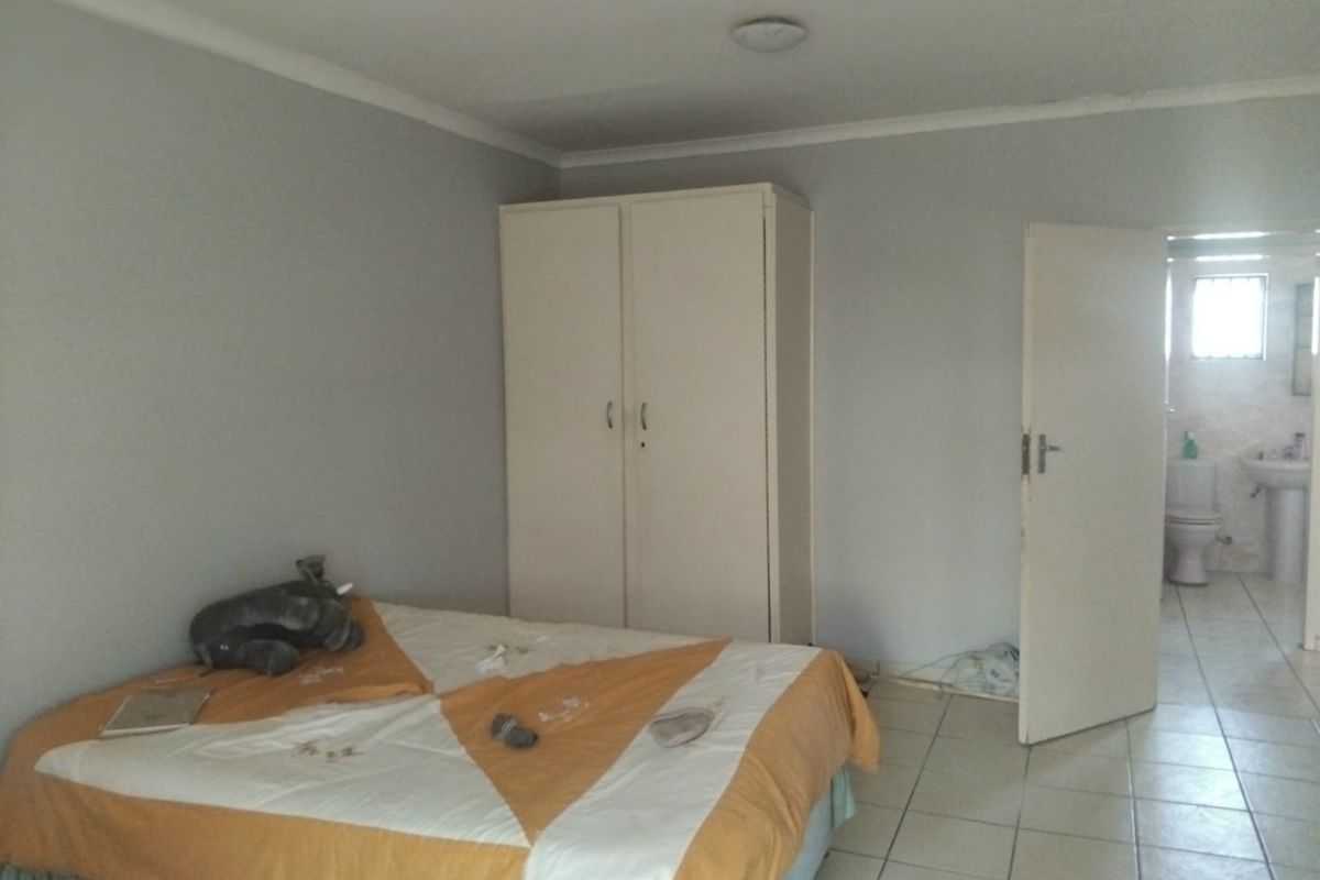 A bedroom featuring tiled flooring and a built-in wardrobe, with an adjoining bathroom visible through the doorway.