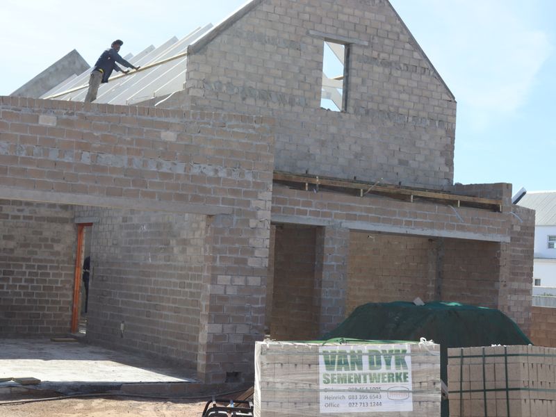 A residential property currently under construction, featuring exposed concrete block walls and roof framing in the early stages of development.