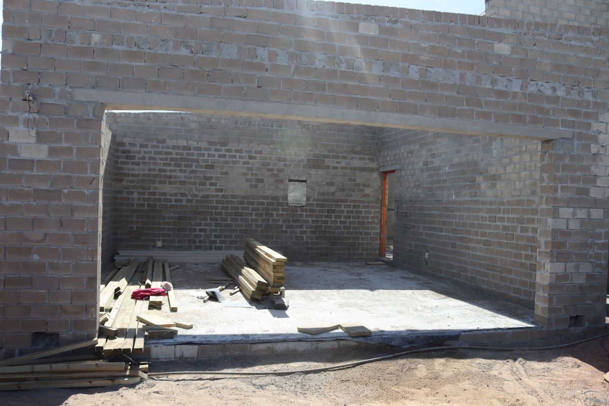 An unfinished living area under construction featuring exposed concrete block walls and a concrete floor slab, ready for final finishes and interior design.