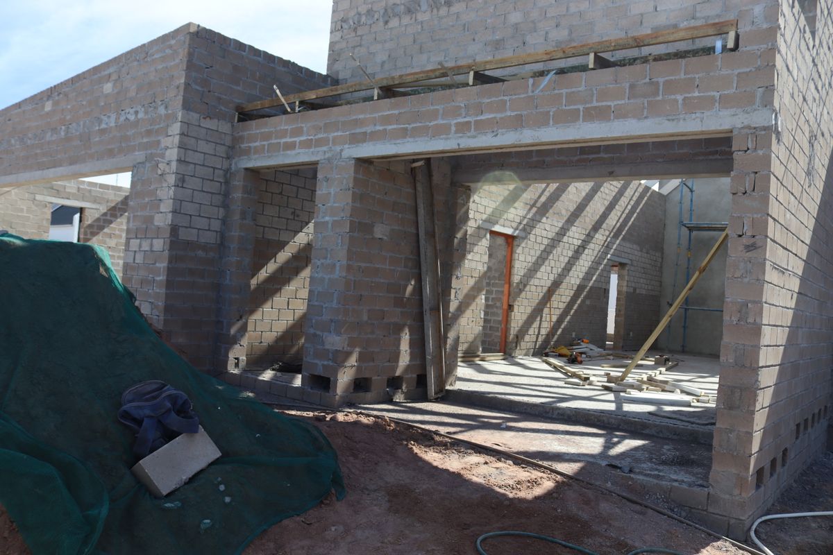 A construction-phase view of a residential property showing exposed concrete block walls and structural framing for an open-plan living area.