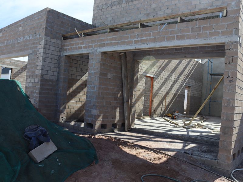 A construction-phase view of a residential property showing exposed concrete block walls and structural framing for an open-plan living area.