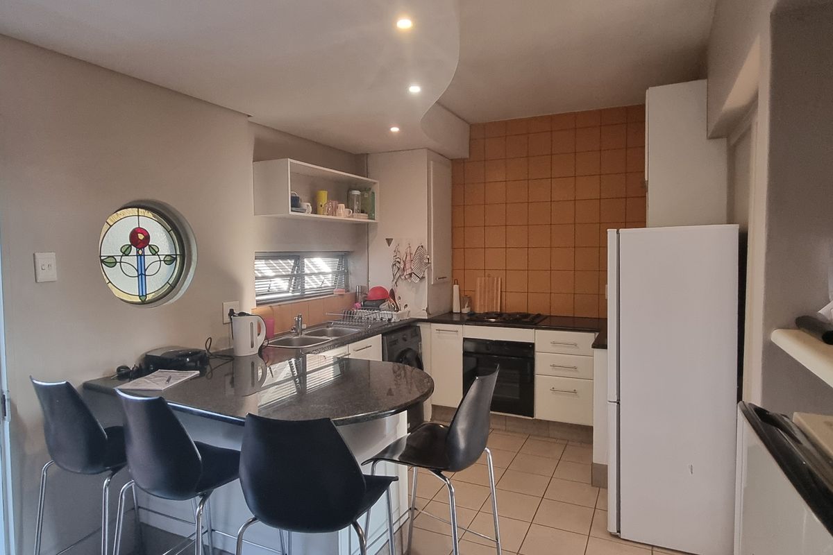 Compact kitchen featuring granite countertops, built-in oven, gas hob, and a unique stained glass window, offering a functional and characterful cooking space.