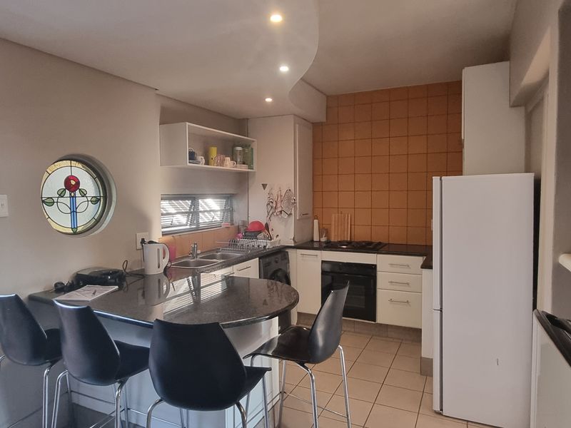 Compact kitchen featuring granite countertops, built-in oven, gas hob, and a unique stained glass window, offering a functional and characterful cooking space.