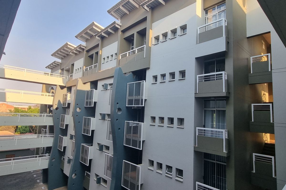 Exterior view of a modern apartment complex featuring multi-level balconies, walkways, and a structured facade design.