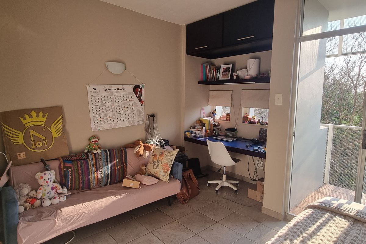 Bedroom featuring tiled flooring, a built-in desk with overhead storage, and a sliding glass door providing access to a private balcony.