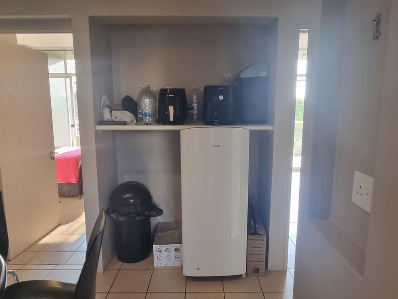A utility alcove featuring built-in shelving and tiled flooring, providing functional storage space within the flat.