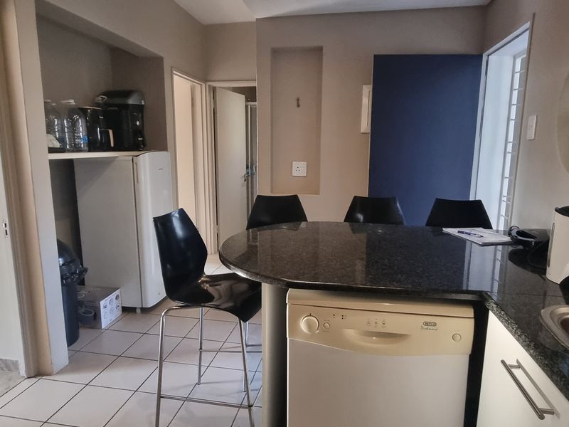 A functional kitchen area featuring granite countertops, a stainless steel sink, integrated dishwasher, and a unique circular stained glass window.