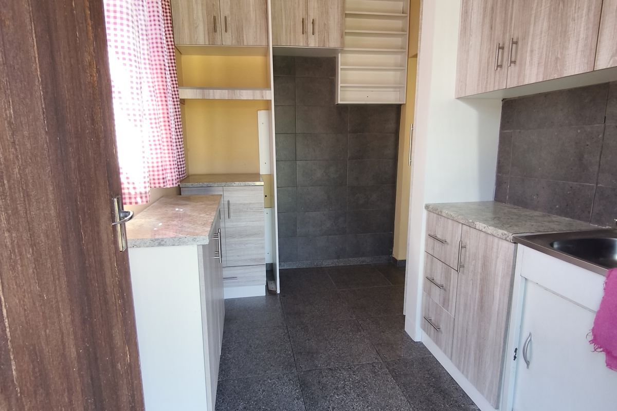 A functional kitchen space featuring laminate cabinetry, tiled backsplash, and tiled flooring, offering a clean and practical layout for culinary activities.