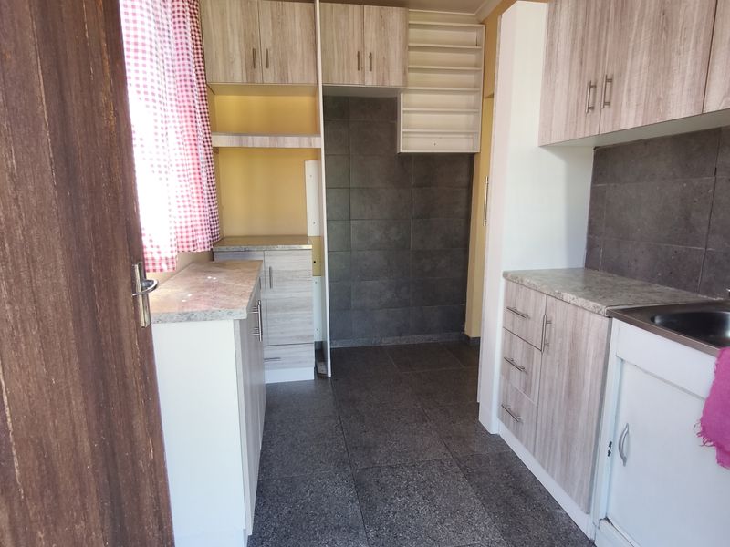 A functional kitchen space featuring laminate cabinetry, tiled backsplash, and tiled flooring, offering a clean and practical layout for culinary activities.