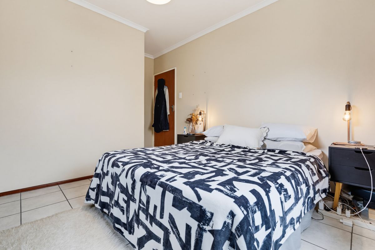 A functional bedroom featuring tiled flooring, neutral wall finishes, and a standard interior door.