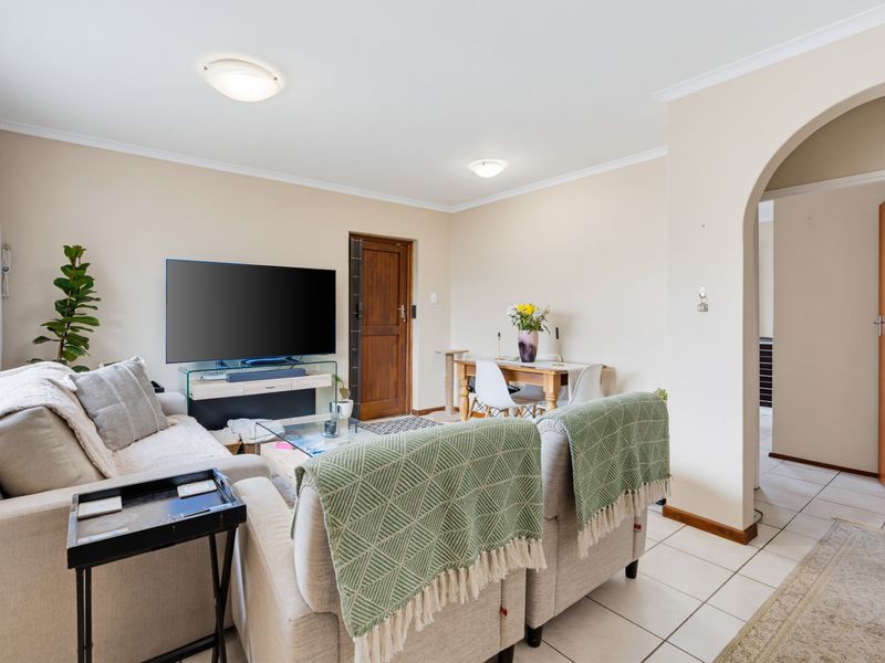 An open-plan living and dining area featuring tiled flooring, a distinctive arched entryway, and neutral wall finishes.