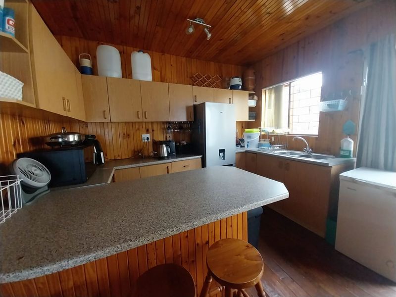 A functional kitchen featuring timber wall and ceiling paneling, laminate cabinetry, a breakfast bar, and a double bowl sink.