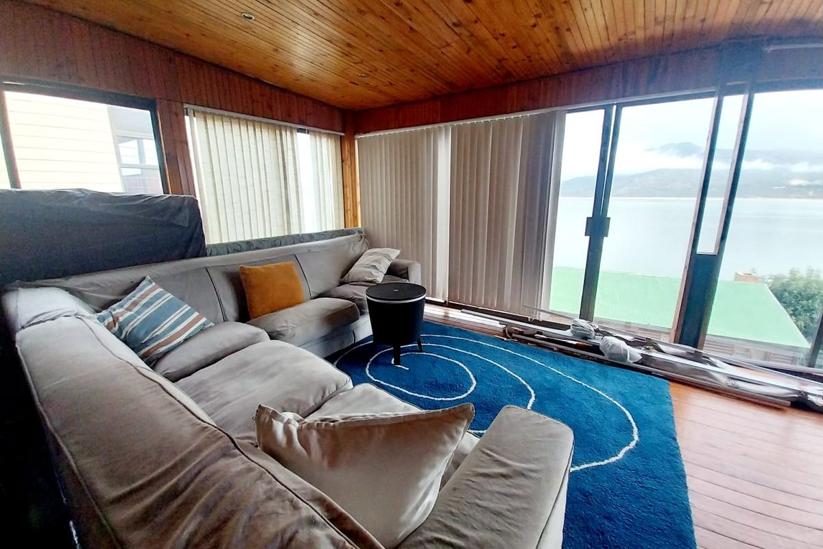 Living room featuring timber-clad ceilings, timber flooring, and large sliding glass doors offering expansive views and natural light.