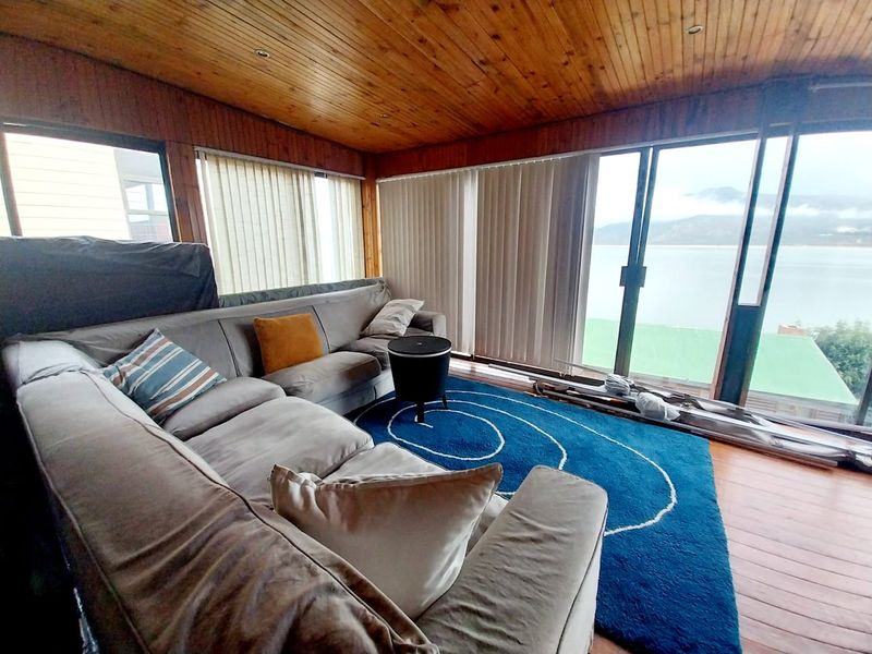 Living room featuring timber-clad ceilings, timber flooring, and large sliding glass doors offering expansive views and natural light.
