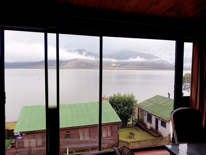 A scenic view of the lake and mountains framed through large sliding glass doors from an interior living space.