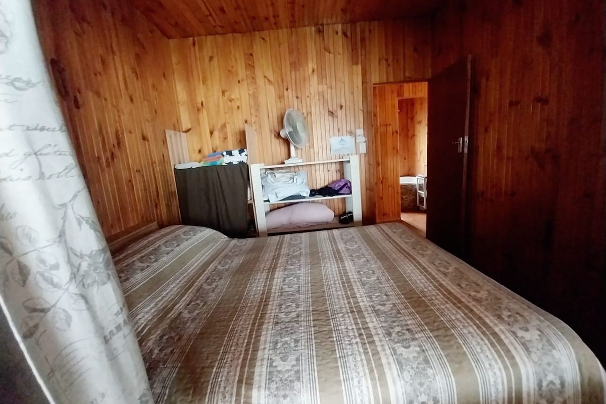 A bedroom featuring extensive timber wall and ceiling paneling, providing a rustic aesthetic that could be updated for a more modern feel.