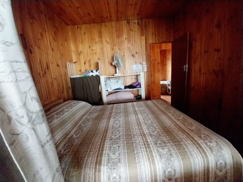 A bedroom featuring extensive timber wall and ceiling paneling, providing a rustic aesthetic that could be updated for a more modern feel.
