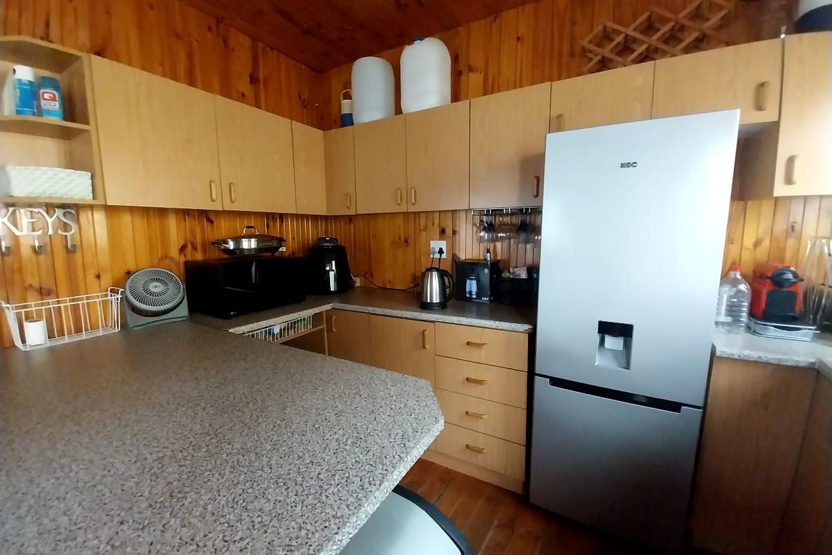 A functional kitchen featuring timber wall paneling, laminate cabinetry, and stone-look countertops, offering a traditional aesthetic with ample storage space.