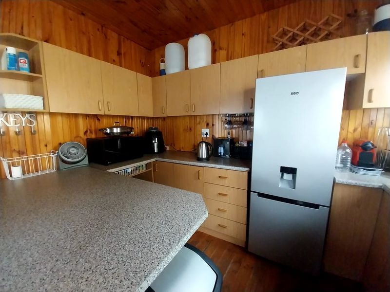 A functional kitchen featuring timber wall paneling, laminate cabinetry, and stone-look countertops, offering a traditional aesthetic with ample storage space.
