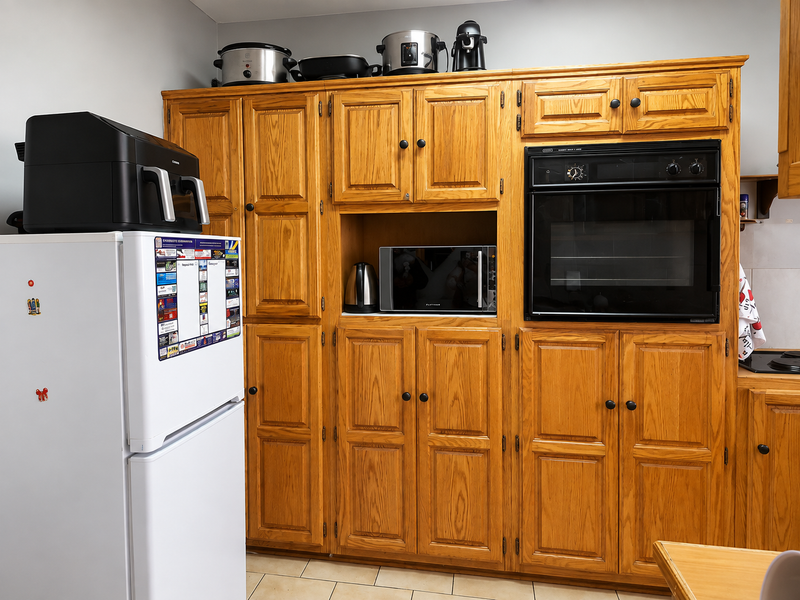 A kitchen featuring traditional oak cabinetry with integrated oven and built-in microwave space, offering ample storage and a classic aesthetic.