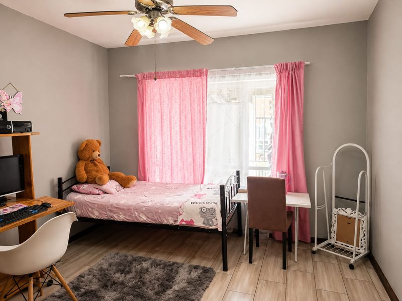 A well-maintained bedroom featuring tiled flooring, a ceiling fan, and a window with natural light.
