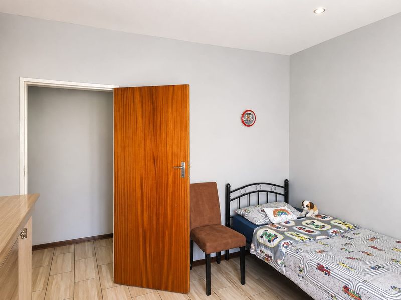 A well-maintained bedroom featuring neutral grey walls, tiled flooring, and recessed downlighting, providing a clean and functional living space.