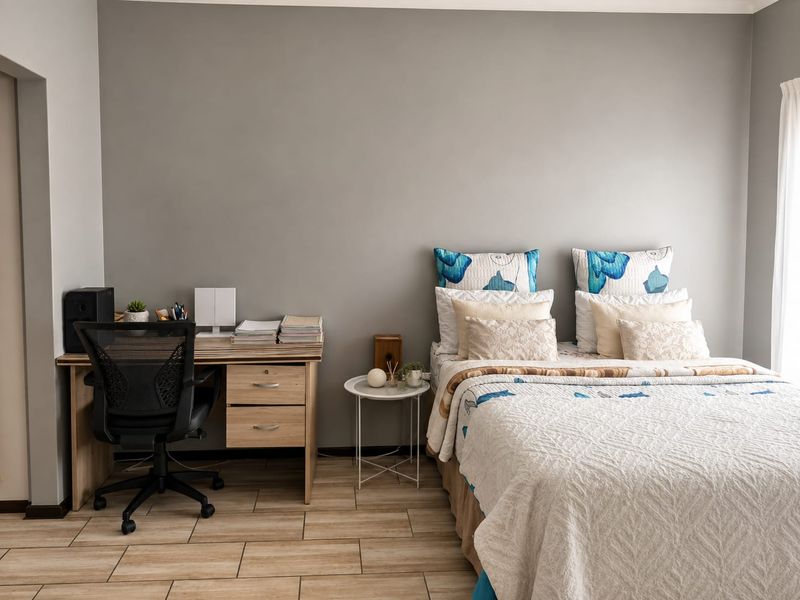 A well-maintained bedroom featuring neutral grey walls and light-toned tiled flooring, providing a clean and functional living space.