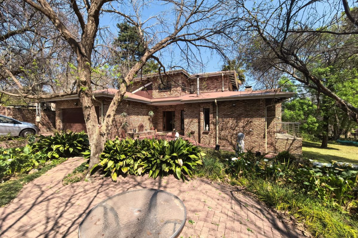 Rear view of a face brick townhouse featuring a paved patio area, established garden, and integrated garage access.