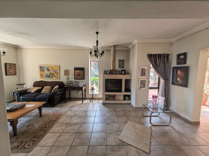 Spacious living room featuring ceramic floor tiles, a built-in fireplace with a stainless steel flue, and direct access to an outdoor area.