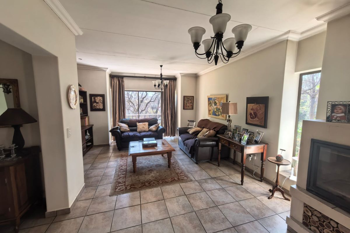 Spacious living room featuring tiled flooring, a built-in fireplace, and elegant ceiling chandeliers, offering a comfortable and well-lit area for relaxation.