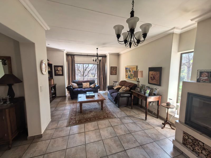 Spacious living room featuring tiled flooring, a built-in fireplace, and elegant ceiling chandeliers, offering a comfortable and well-lit area for relaxation.