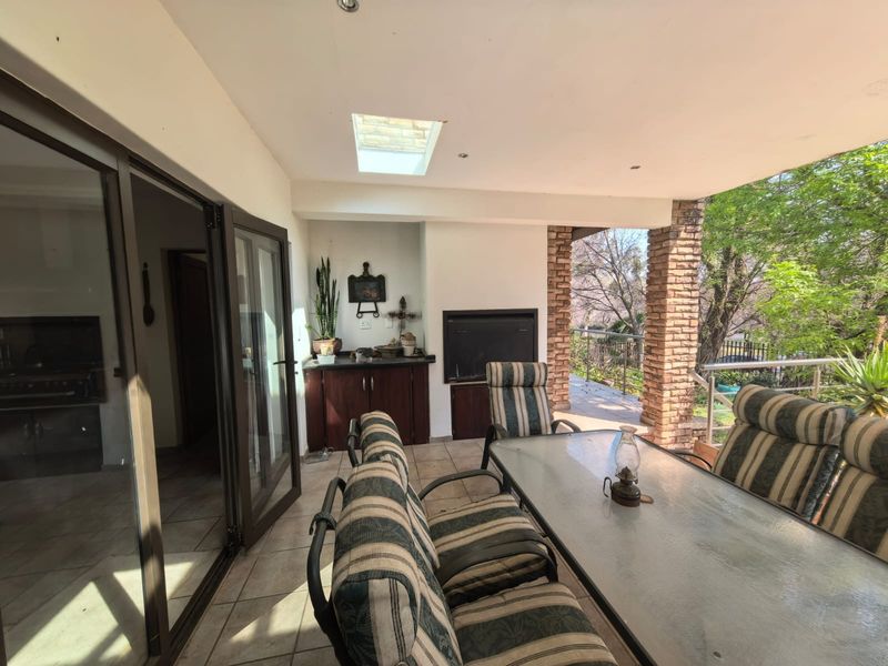 Covered patio featuring a built-in braai, skylight, and tiled flooring, providing a seamless transition to the outdoor garden area.